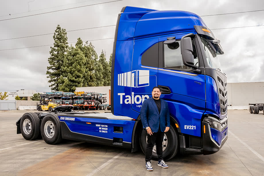 A man standing next to a blue semi truck