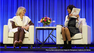 Two women seated on a stage having a conversation