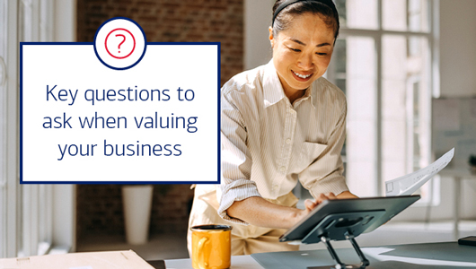 A woman cheerfully enters data on a digital tablet. Text says key questions to ask when valuing your business