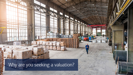 Pallets of goods are stacked in a high-ceilinged industrial building. Text reads why are you seeking a valuation?